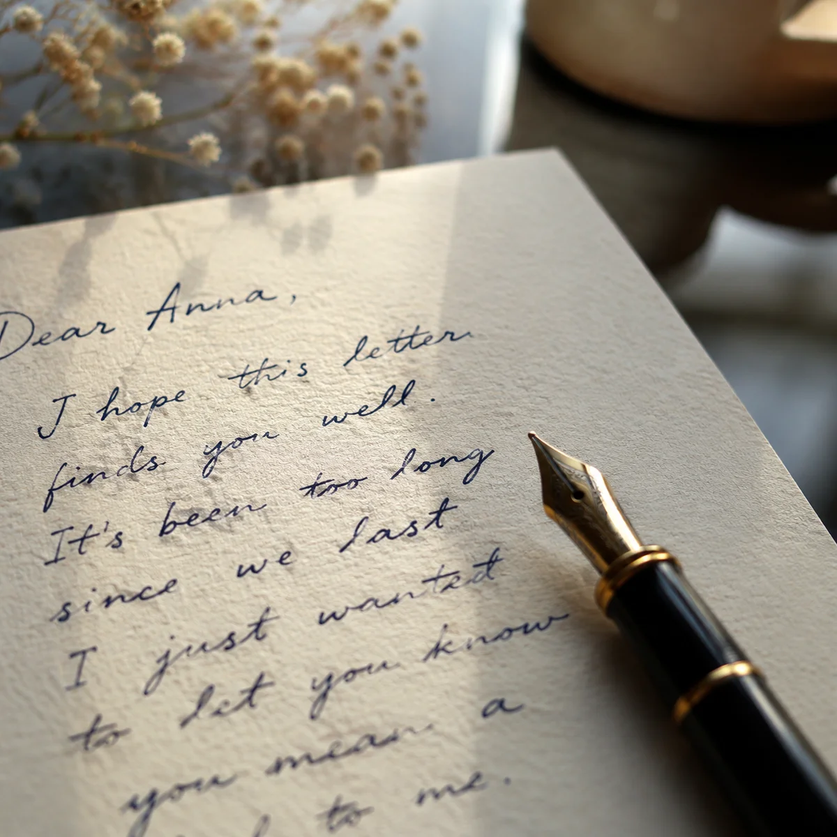 Close-up detail of a handwritten note with words visible next to a pen on warm paper, editorial photography