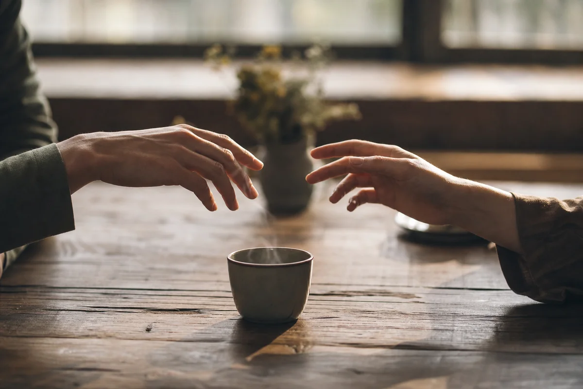 Two hands not quite touching across a table, representing emotional distance in ENM relationships